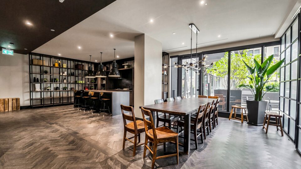 Party room with a long harvest table, industrial kitchen and glass doors to a terrace