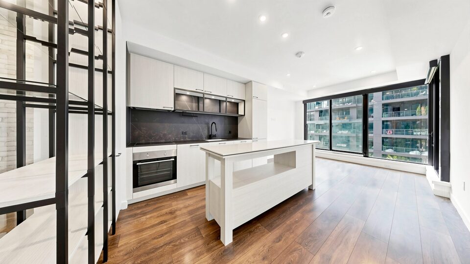 Open kitchen with island, stone backsplash and integrated appliances opening onto the living area