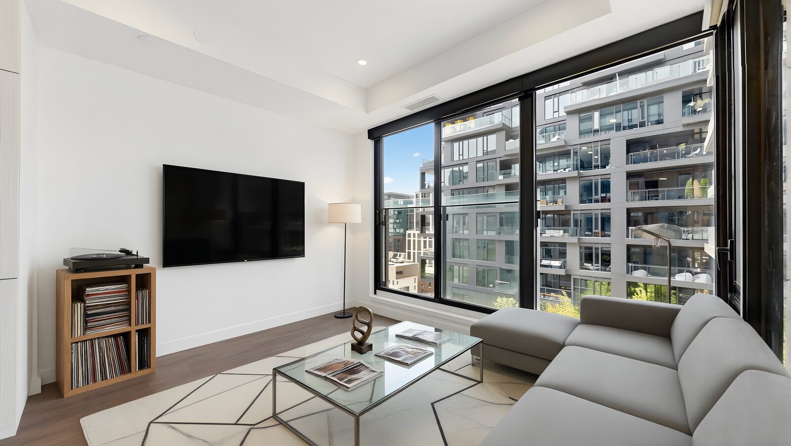 Living room virtually staged with a sofa, wall-mounted television and record player beside floor-to-ceiling windows