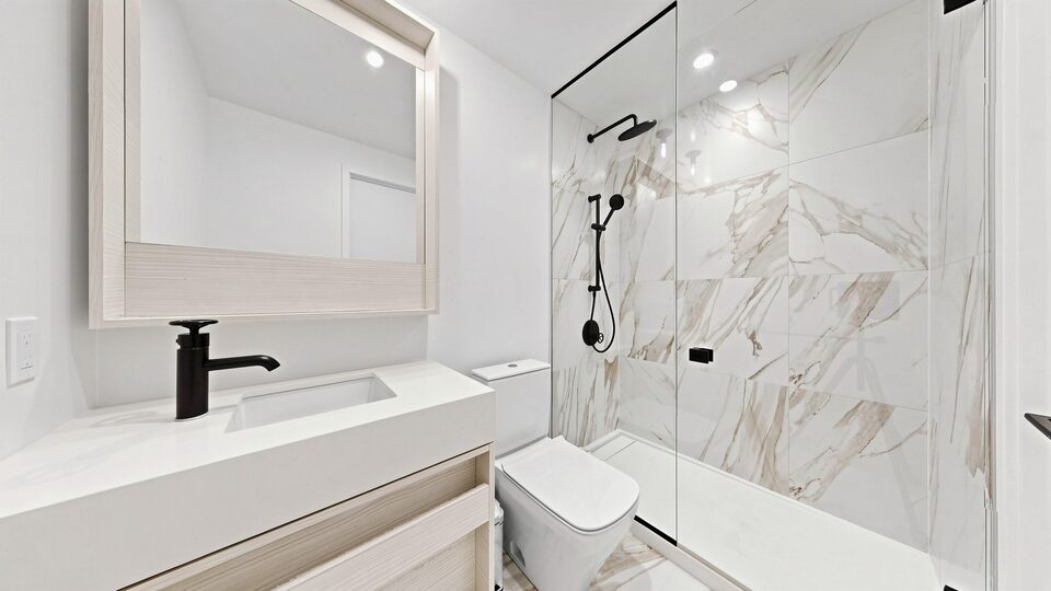 Second bathroom with a walk-in glass shower, marble-look tile and matte black tapware