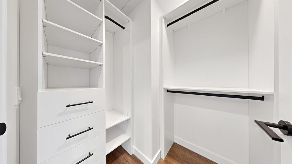 Fitted walk-in closet with white shelving, drawers and matte black hanging rails
